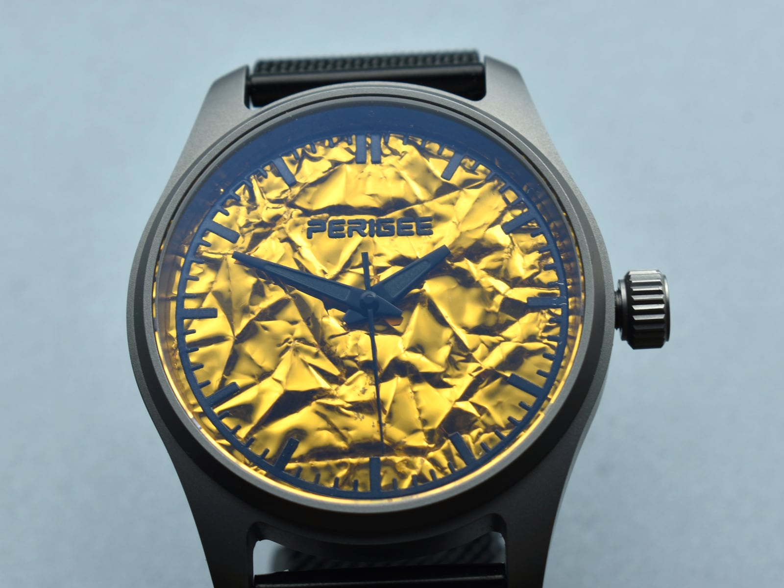 The 39 mm PERIGEE Contact Light seen straight on: a gold foil dial with dark baton markers, in a Grade 2 titanium case on a black strap.
